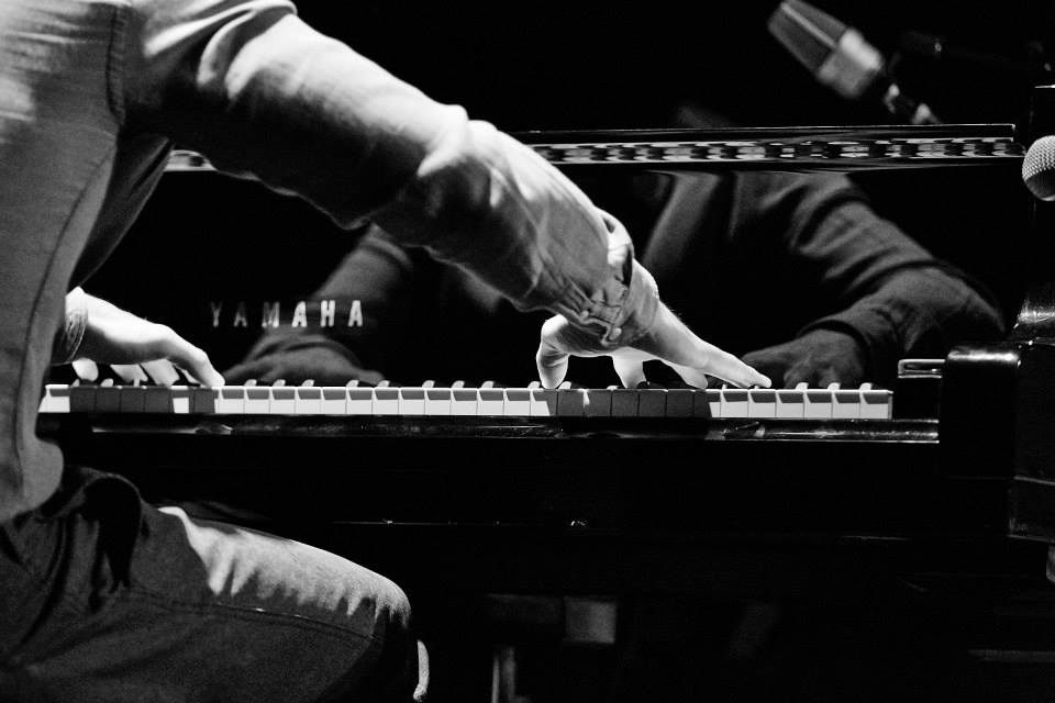 Both hands on the keys of a Yamaha grand piano, in black and white